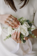 Bride holds wedding bouquet in hand, showing her manicure and wedding rings
