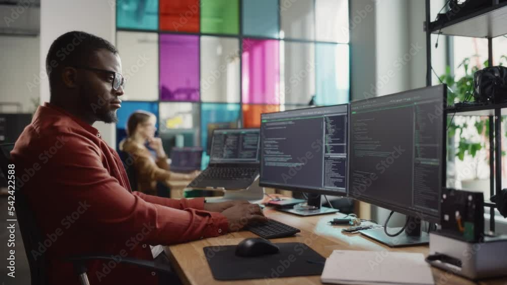 Poster African American Man Writing Code on Desktop Computer With Multiple Monitors Set Up and a Laptop in Creative Office. Professional Data Scientist Using Software to Analyze Information From Internet.
