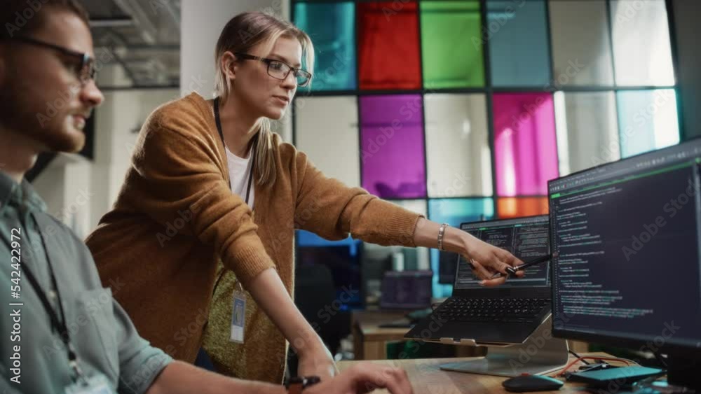 Aufkleber Male Programmer Showing Code on Desktop Computer to Female Lead Developer in Stylish Office Space. Caucasian Woman Helps Her Colleague With Useful Coding Hacks, Points at Erros on Display.