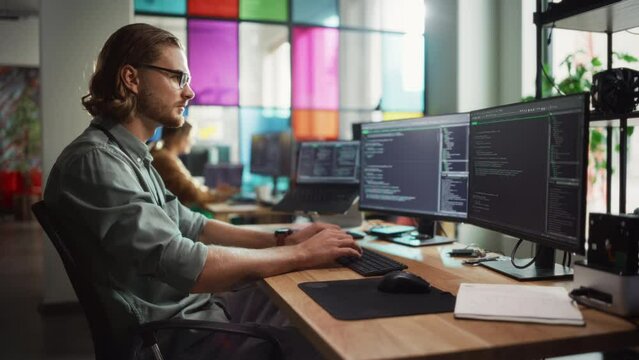 Male Programmer Coding on Desktop Computer With Two Monitors Set Up in Creative Office. Caucasian Man Using Artificial Intelligence to Create Innovative Software for Succesful Start-up Company.