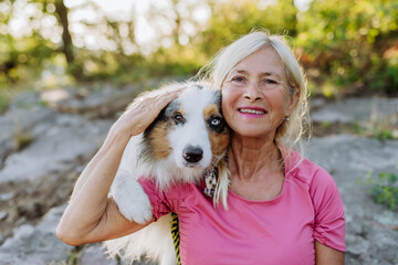 Portrait of senior woman with her dog in forest.