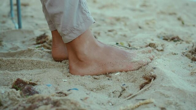 close up female feets and toes on white sand with shells on beach at hot summer sunny day. relax and wellness concept in travel