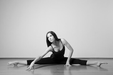 Beautiful young ballerina stretching on the floor before dancing workout in ballet studio