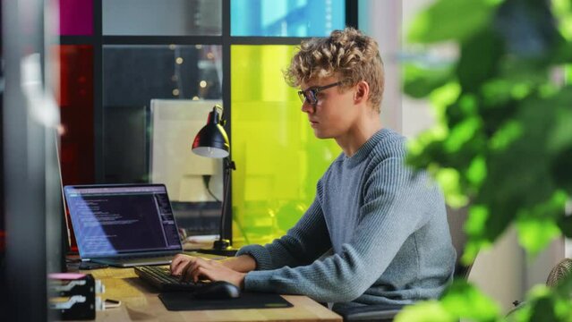 Side View of Male Data Science Intern Writing Lines Of Code on Desktop Computer In Stylish Office. Young Caucasian Man Solving Software Problems for Big Tech Company. Fututre Programmer Learns Coding.