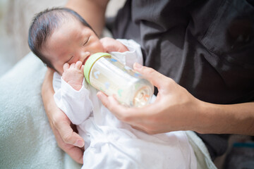 Obraz na płótnie Canvas パパに抱っこされてミルクを飲む生まれたての赤ちゃん