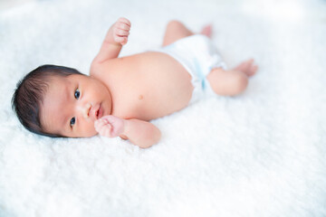 ふわふわのガーゼの上で楽しそうに遊ぶ生まれたての赤ちゃん