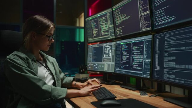 Female Cyber Security Student Coding on Desktop PC With Six Monitors Setup in Dark Office. Caucasian Woman Finishes Internship for Big IT Company. Monitoring Protection System, SAAS Server Data