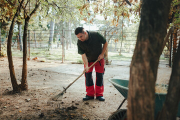 Caretaker with down syndrome in zoo cleaning animal enclosure. Concept of integration people with...
