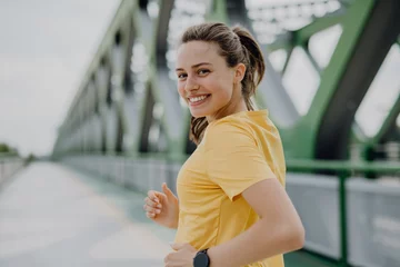 Tuinposter Young woman jogging at city bridge, healthy lifestyle and sport concept. © Halfpoint
