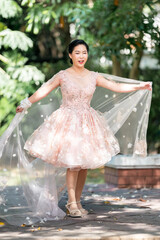 Asian girl in an old rose pink color knee length fluffy dress with high heel slingback shoes and...