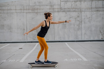 Young woman ridding skateboard at city. Youth culture and commuting concept.