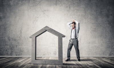 Determined banker man in empty concrete room breaking dollar figure
