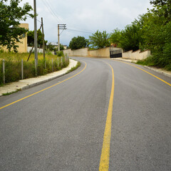 A quiet winding town road, clean and yellow lined asphalt road