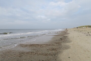 Spaziergänger gehen im Herbst am Strand der Nordseeinsel Baltrum entlang. Mitte Oktober stehen noch Strandkörbe am Strand der Insel.