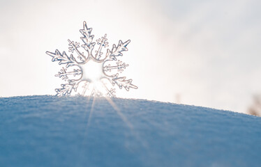 Beautiful ice crystal lies in the snow and glistens in the sun, bokeh in the blue background