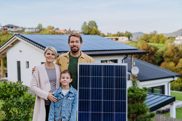 Happy family near their house with solar panel. Alternative energy, saving resources and...