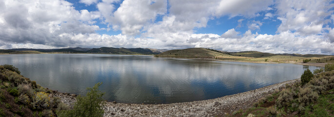 Panorama shot of a lake in the Dixie National Forest, with blue skies and white clouds reflected in the water, Utah, USA