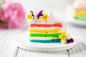 Obraz na płótnie Canvas Delicious rainbow cake on plate on table on light wooden background