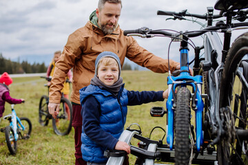 Young family with little children preparing for bicycle ride in nature, putting off bicycles from...