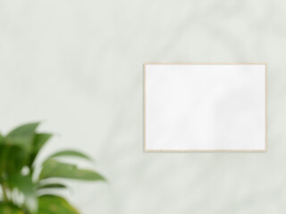 Horizontal wooden frame mockup on white wall. Poster mockup. Clean, modern, minimal frame. Empty frame Indoor interior, show text or product. frame mockup with shadow and plant. 3d rendering.