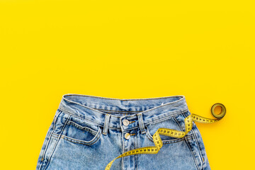 Yellow measuring tape into jeans as weight loss concept. Weight loss and diet concept