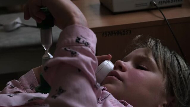 Physiotherapy for sinusitis. Impact on the maxillary sinuses. A teenage girl lies on a couch and holds an apparatus for the treatment of sinusitis