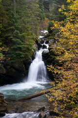 Waterfall flowing through rocks in a deep forest, autumn landscape - 542437500