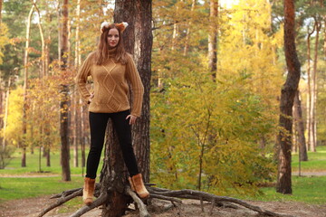 Young woman near the tree in autumn forest