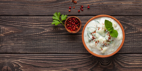 Indian Fresh sauce called Raita with herbs, dahi and sliced cucumber in a bowl on the table. Top view, Copy space