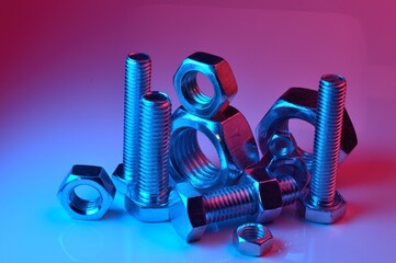 large and small nuts and bolts, highlighted in different colors, on a light background