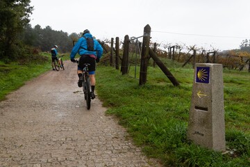 Pilgrims on bicycles near a milestone on the Camino de Santiago Portugues in Caldas de Reis