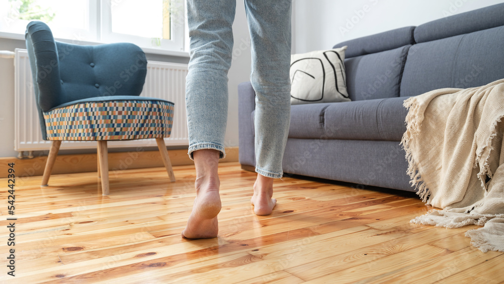 Poster woman in jeans walking barefoot in room