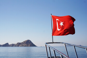 Prow of the yacht with the Turkish flag in the sea. Excursion on the ship. In the sea near the island of Suluada.