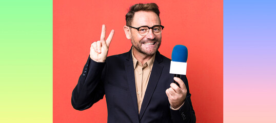 middle age man smiling and looking friendly, showing number two. journalist and a microphone concept
