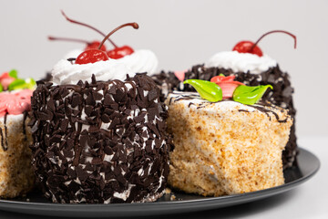 Cakes with chocolate, cherries and cream on a white background.