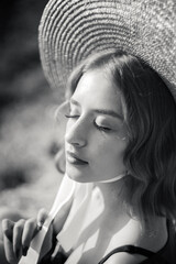 Black and white portrait of stylish girl in straw hat posing on a background of the city.