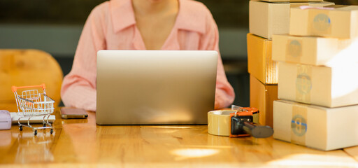 Close-up shot of an Asian woman working with boxes at home at work. Starting a small business owner Entrepreneurship, small business, SME or freelance online and delivery ideas.