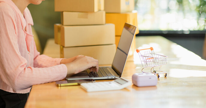 Close-up shot of an Asian woman working with boxes at home at work. Starting a small business owner Entrepreneurship, small business, SME or freelance online and delivery ideas.