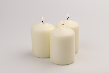 Fototapeta na wymiar Burning white wax candles on white background.
