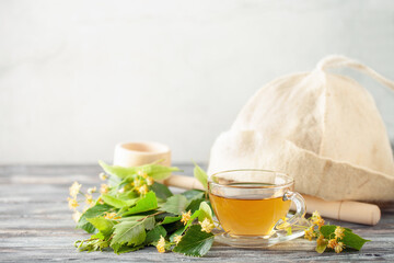 Glass teacup of green tea and linden flowers and birch leaves on wooden background. Herbal hot drink. Sauna concept