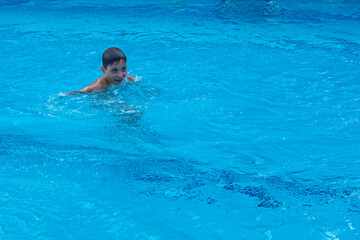 happy boy swims in the pool. family holiday