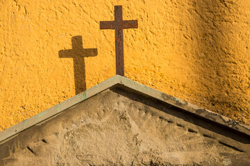 Cross on a tombstone at a yellow wall