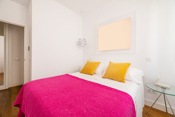 Bedroom with double bed with bright pink bedspreads and yellow cushions