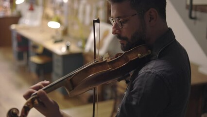 Adult bearded luthier playing hand crafted violin