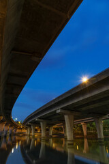 Underside of an elevated road across river at dusk