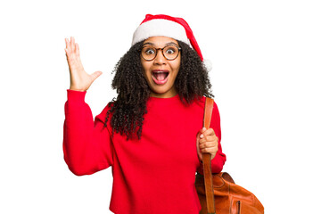 Young african american student woman wearing a christmas hat isolated receiving a pleasant surprise, excited and raising hands.