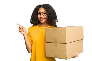 Young african american woman moving to other house while picking up a box full of things isolated smiling and pointing aside, showing something at blank space.