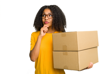 Young african american woman moving to other house while picking up a box full of things isolated looking sideways with doubtful and skeptical expression.