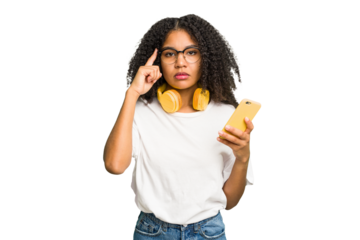 Young african american woman listening to music with yellow headphones isolated pointing temple with finger, thinking, focused on a task.