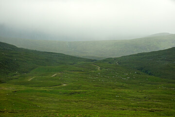 Fototapeta na wymiar A winding road disappears into the mist in the Highlands of Scotland.